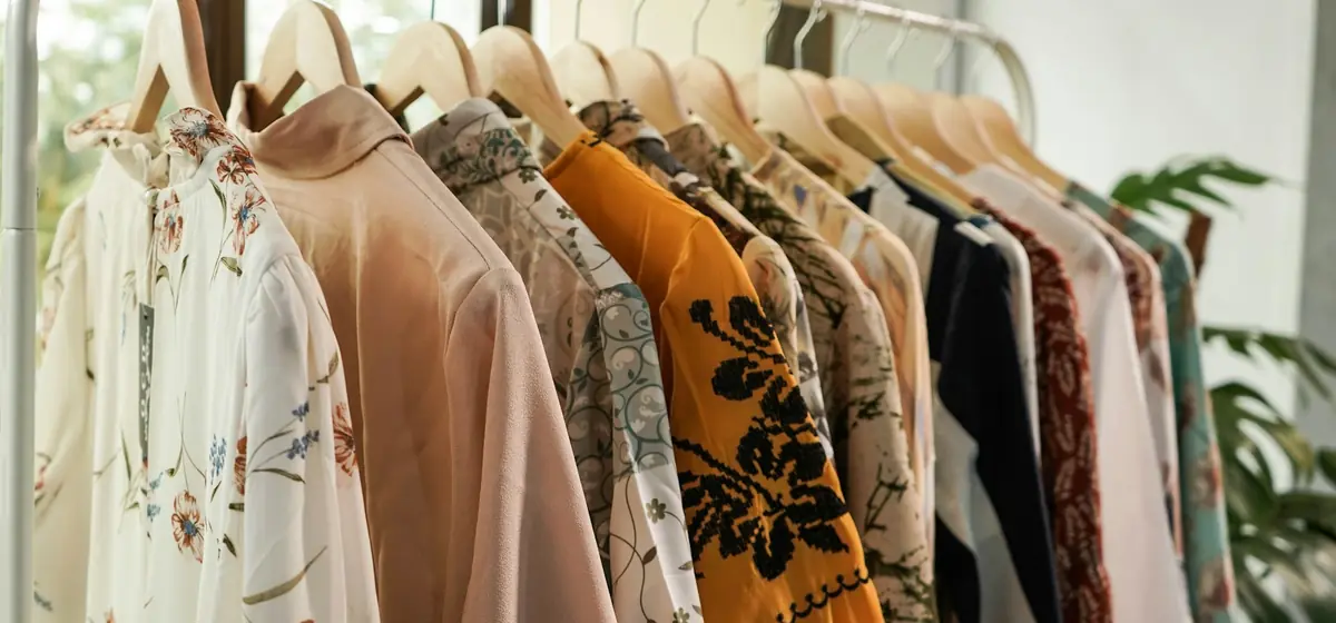 Arara de roupas com blusas estampadas e lisas em cabides de madeira